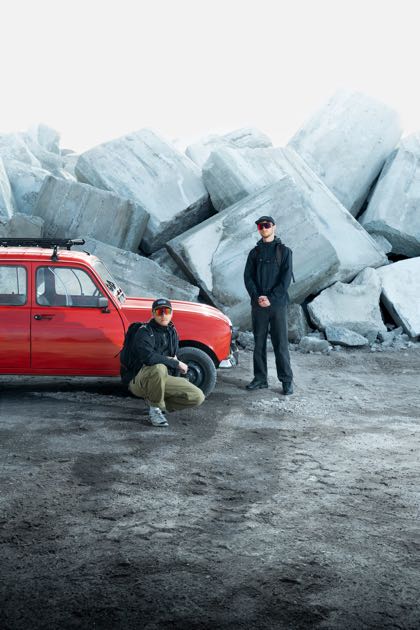 La 4L rouge devant les blocs de béton empilés, les deux équipiers à côté